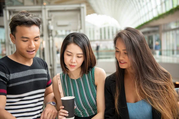 ショッピングセンターでコーヒーを飲みながら話している3人のアジア人の友人 — ストック写真