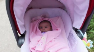 Bebek hareket ediyor ve bebek arabasında yatarken komik yüz ifadeleri takınıyor.