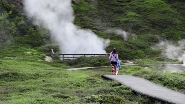 Craters of The Moon Geysers Park, New Zealand. Mother and daughter walking along the trail with steam from geothermal valley. Slow motion — Stock Video