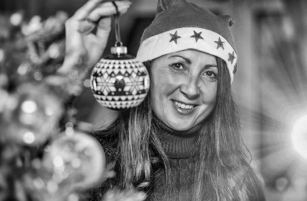 幸せなブルネットの女性が自宅でクリスマスツリーを飾る 赤いクリスマスボールを保持 — ストック写真