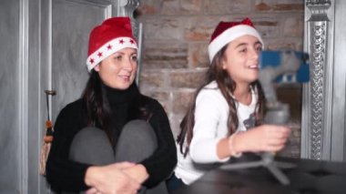 Noel 'de Noel Baba Şapkası takan bir kadın ve kızı aileleriyle video görüşmesi yapıyor.