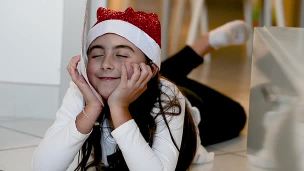Evde yerde yatan ve elinde Noel Baba 'ya mektup tutan genç bir kız. Noel rüyaları ve tatil konsepti — Stok video