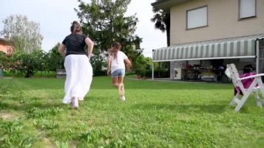 İki genç kız dışarıda vakit geçiriyorlar, çimenlerde koşuyorlar, arkadan bakıyorlar, ağır çekimde.