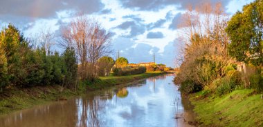 Şafak vakti Toskana kırsalında. Ağaçları ve gökyüzü olan güzel bir dere, İtalya
