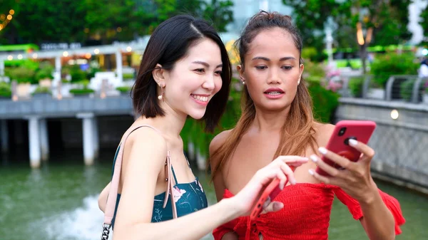 2人の美しい若いアジアの女性が話して 笑顔で 街の通りを歩いてリラックスし 彼らのスマートフォンを見て — ストック写真
