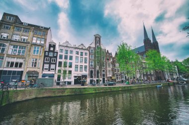 AMSTERDAM, NETHERLANDS - 25 Nisan 2015: Kanal üzerindeki geleneksel evler ve binalar.
