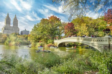 Bow Köprüsü ve Central Park 'taki Göl' ün üzerinde inanılmaz bir gün batımı. New York şehrinin yeşillik renkleri.