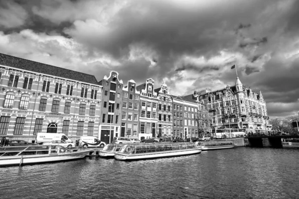 AMSTERDAM, NETHERLANDS - 25 NİSAN 2015: Kanalda tekneli geleneksel evler ve binalar.