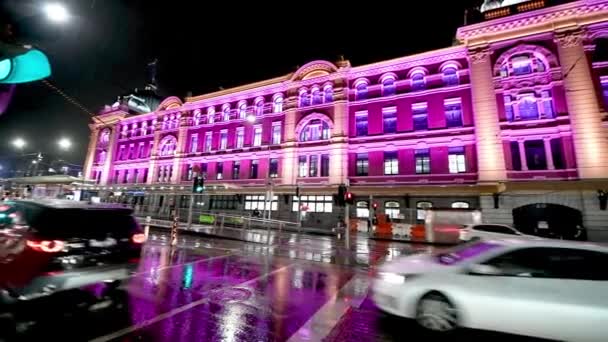 MeLBOURNE, AUSTRALIA - 2018年9月：雨夜，著名的Flinders中央车站前的夜间街道交通。慢动作 — 图库视频影像