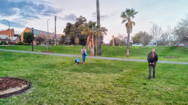 Şehir parkında ailesiyle dron kullanan bir adam..