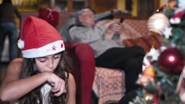 Dvě mladé sestry doma zdobí vánoční stromek na sobě Santa Klobouk — Stock video