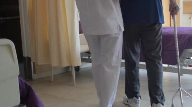 Afrikalı doktor olgun yaşlı bir adamın yatmasına yardım ediyor.