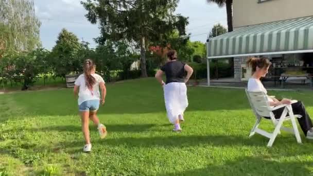 Duas meninas desfrutando de tempo ao ar livre, correndo na grama, visão traseira, câmera lenta — Vídeo de Stock