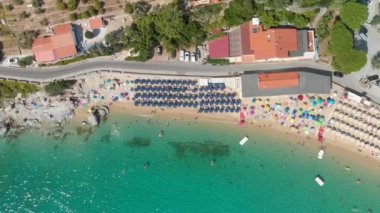 Tropikal bir plajdaki çizgili plaj şemsiyelerinin hava manzarası.