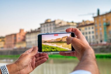 Floransa, İtalya 'yı keşfetmek. Arno nehri boyunca akıllı telefonlu binaların fotoğraflarını çeken adamın elindeki detaylar.