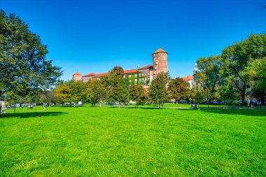 KRAKOW, POLAND - 1 Ekim 2017: Turistler güneşli bir günde ortaçağ simgeleriyle güzel bir şehir parkını ziyaret ettiler.