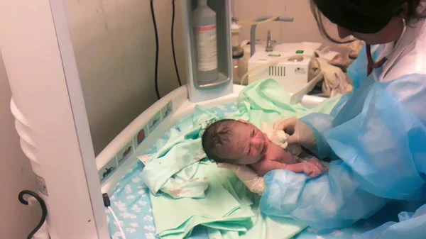 医者小児科医は診療所で赤ん坊を検査新生児はベッドで泣いて — ストック写真