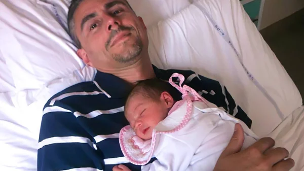 Father with newborn bay in hospital delivery room.