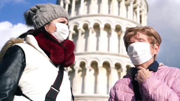 Two women talking outdoor with face masks in front of a landmark. Pandemic concept — Stok video