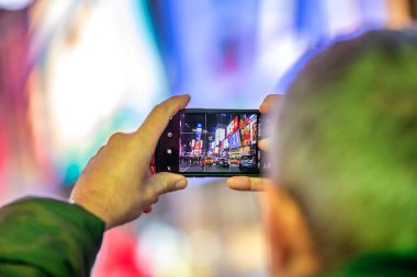 NEW YORK CITY - 3 ARALIK 2018: Bilinmeyen adam gece Times Meydanı 'nı akıllı telefonla çekiyor.