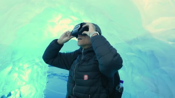 Человек в очках виртуальной реальности исследует ледяную пещеру — стоковое видео