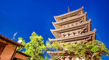 Antik Budist tapınağı Hokan-ji eski Kyoto kasabasında gecenin erken saatlerinde. Mavi parlayan gökyüzü geleneksel pagoda ile çelişiyor.