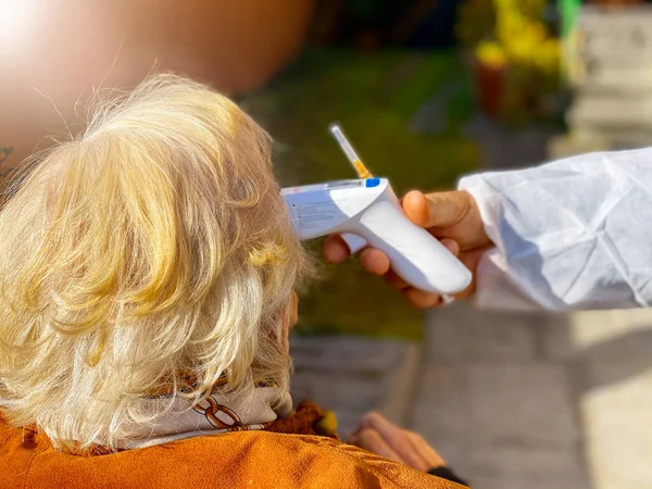 Przygotowanie Podania Covid Szczepionki Zewnątrz Lekarz Mierzący Gorączkę Starszej Kobiecie — Zdjęcie stockowe