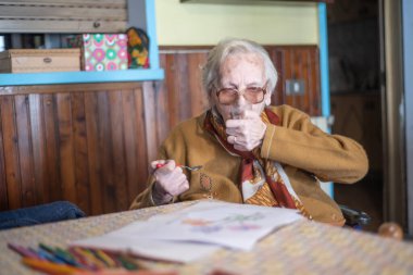 Evde bir fincan kahve yudumlayan yaşlı kadın..