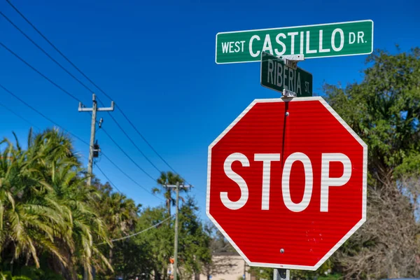 Stop sign and street signs in Florida with palms and beautiful blue sky.