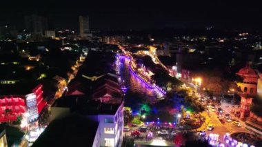 Melaka, Malezya. Geceleri nehir boyunca şehir evlerinin insansız hava görüntüsü. Şehir ışıkları ve yansımaları, Malacca