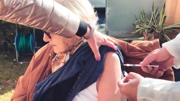 Mujer anciana en los años 90 vacunándose para la pandemia de covid-19 al aire libre — Vídeos de Stock