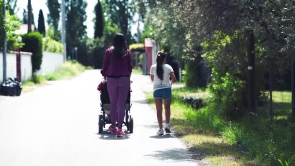 Mujer asistiendo a la madre en silla de ruedas caminando por una calle de la ciudad con su hija. Tres generaciones de personas, cámara lenta — Vídeos de Stock