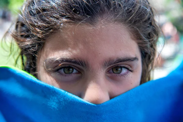 有一双漂亮绿色眼睛的小女孩藏着一条蓝色毛巾 — 图库照片