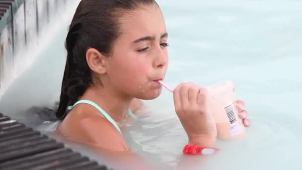 Chica joven relajante sorbiendo jugo de frutas en una piscina natural — Vídeo de stock