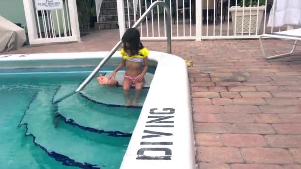 Jeune fille jouant avec sa poupée le long de la piscine de l'hôtel — Video