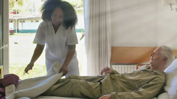 若いアフリカの女性医師は 病院のベッドで老人を助ける — ストック写真