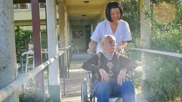 Asyalı Kadın Doktor Hastane Bahçesinde Tekerlekli Sandalyede Yaşlı Bir Adamla — Stok fotoğraf