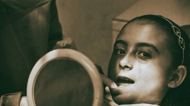 Beyaz lateks eldivenli beyaz dişçi kadın dişlerinin durumunu kontrol ediyor. Mavi dişçi koltuğundaki bebek.