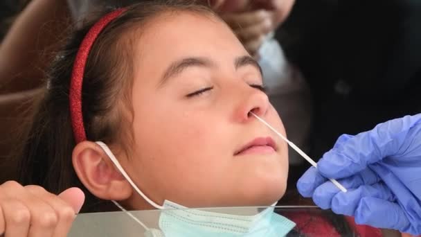 Pediatrician taking nasal mucus test sample from elementary age girls nose performing respiratory virus testing procedure at drive-thru — Stock Video