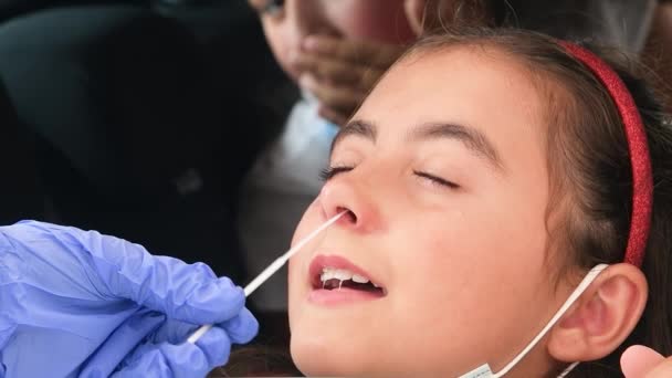 Pediatrician taking nasal mucus test sample from elementary age girls nose performing respiratory virus testing procedure at drive-thru — Stock Video