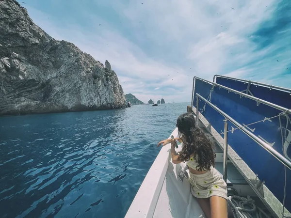 Back view of beautiful woman in a boat visiting Faraglioni in Capri