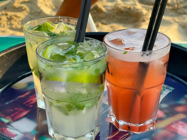 Red and green glasses of aperitif. Appetizers on a gtray on the beach. Summer vacation