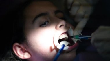 Stüdyodaki genç bir kıza diş teli takan bir dişçi.