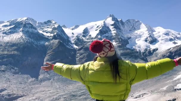 Achteraanzicht van een vrouw die frisse lucht omarmt met bergen bedekt met sneeuw in het zomerseizoen, Grossglockner National Park, Oostenrijk — Stockvideo