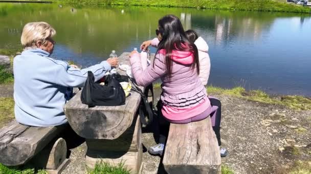 Счастливая семья устраивает пикник на прекрасном альпийском озере. — стоковое видео