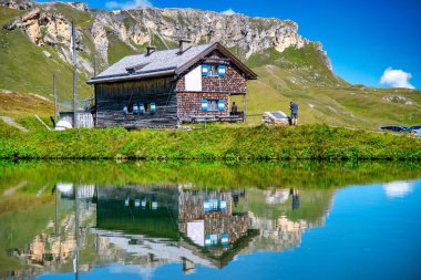 Güzel Alpin yaz manzarasında ahşap bir kulübenin inanılmaz yansıması.