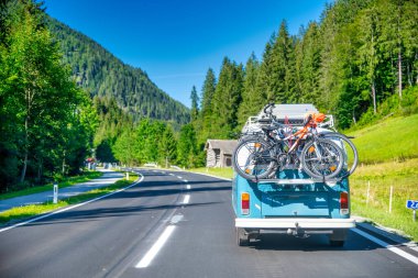 Bisikletler eski mavi bir otobüsün arkasında, Alpin Park 'a giden yolda taşınıyor.