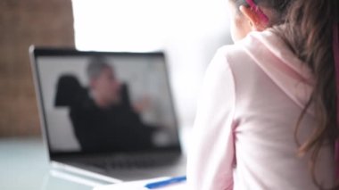 Evde eğitim kavramı. İlkokuldaki genç kız öğretmeniyle birlikte evden ders alıyor.