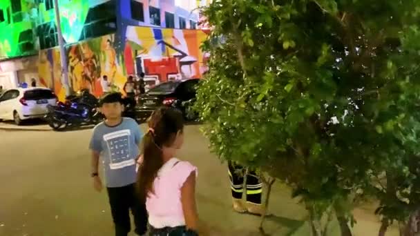 MALACCA, MALAYSIA - 29. DEZEMBER 2019: Ein junges Mädchen besucht nachts die Stadt am Fluss — Stockvideo