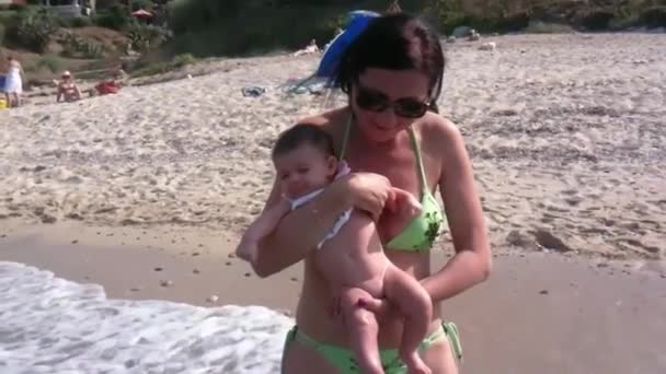 Fiatal baba a tengerparton, aki először érintkezik vízzel. — Stock videók